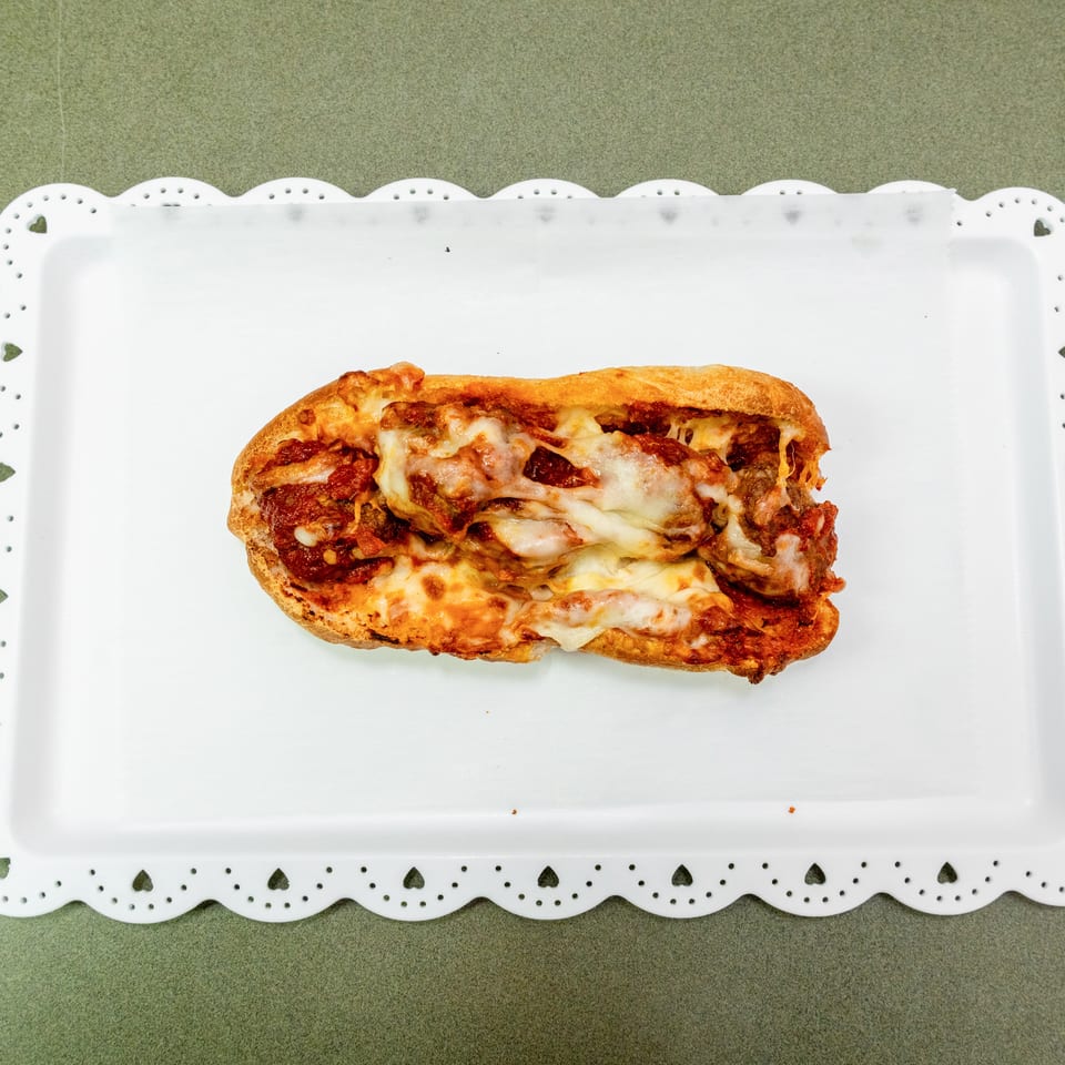 Cheesy pepperoni pizza sandwich served on a decorative white rectangular platter.